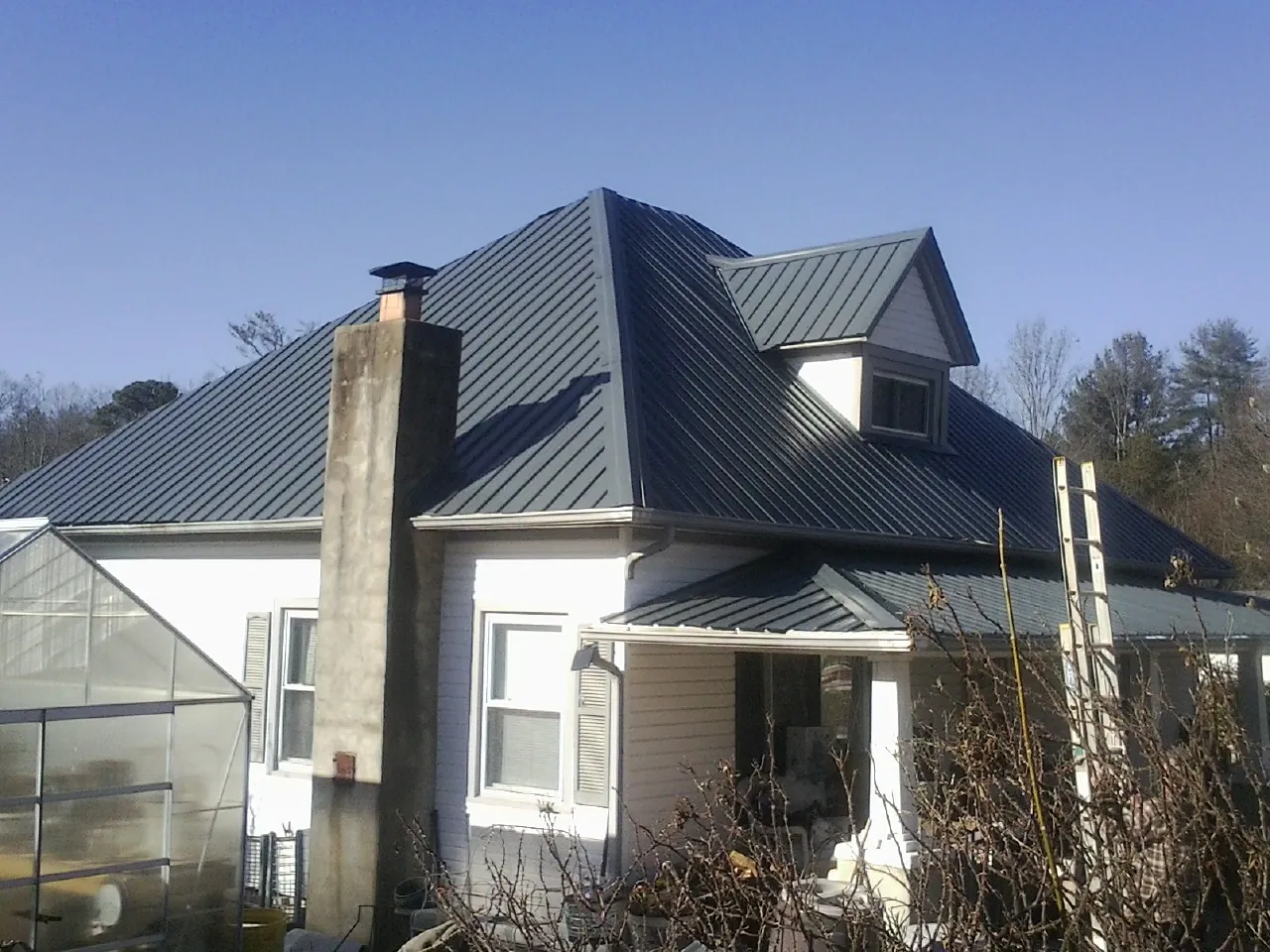 Dark blue standing seam metal roof on a white farmhouse with dormer — Slate & Tile Roof Repair by Roofing Brothers in Pocono Pines