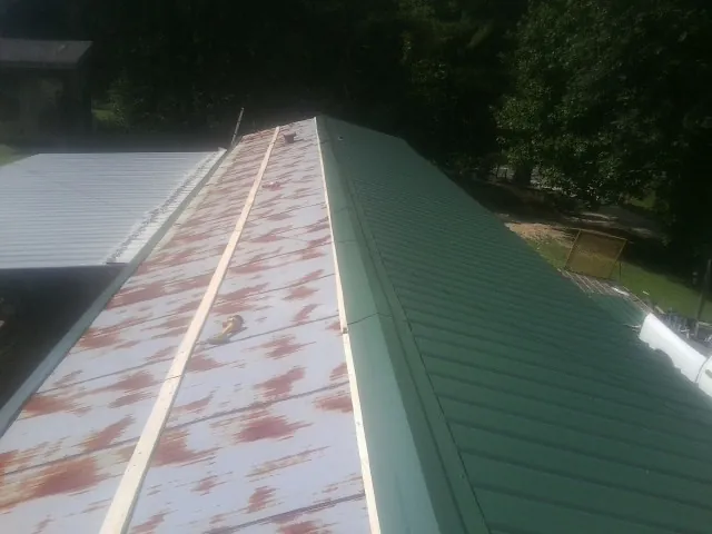Old rusted panels beside newly installed green metal roofing — Wind Damage Roof Repair by Roofing Brothers in Pocono Pines