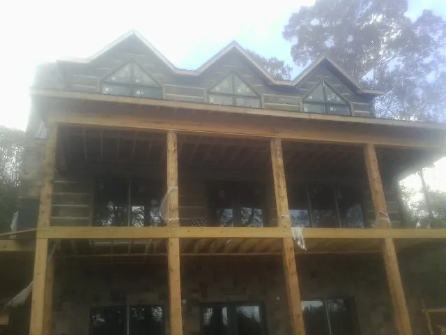 Dormers and porch framing on a large log home under construction — Roof Coating work by our crew in Pocono Pines