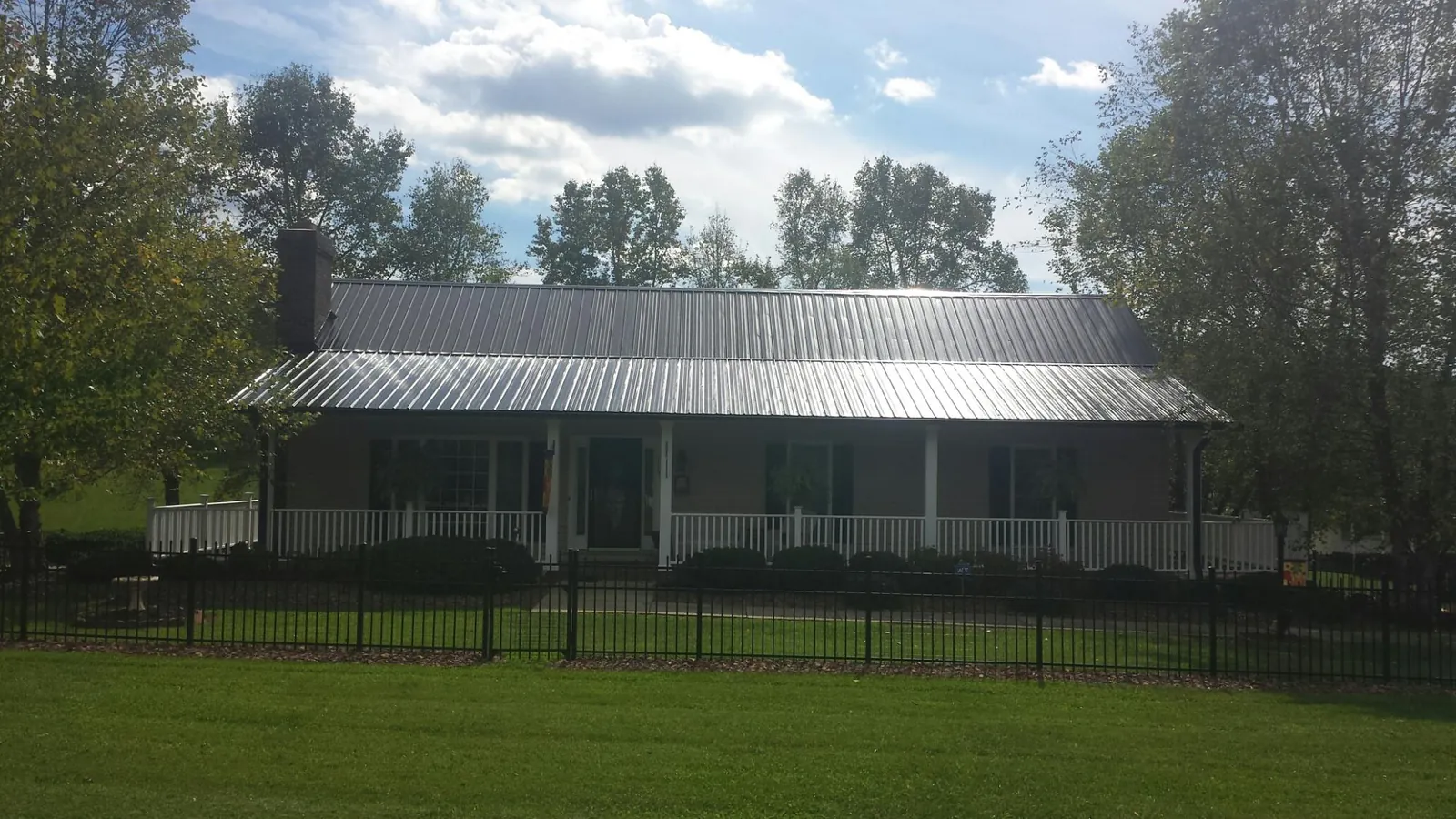 Gray metal roof on a brick ranch with a full width front porch — Gutter Guard Installation work by our crew in Pocono Pines