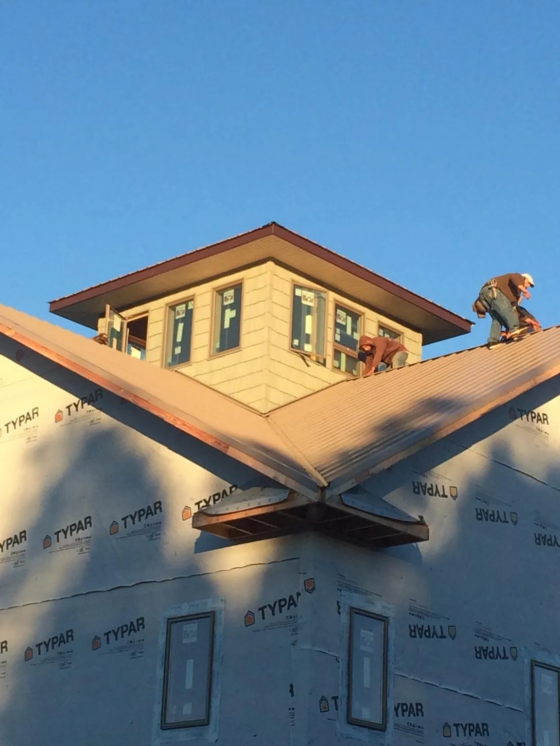 Roofers working around a rooftop cupola on a new metal roof at sunset — Roof Waterproofing in Pocono Pines by Roofing Brothers